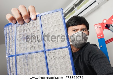 a man with mask showing dirty air filter before cleaning