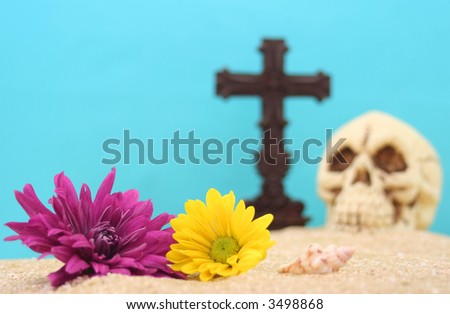 Flowers With Skull and Cross on Sand With Blue Background. Shallow DOF, Focus on Flowers