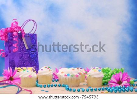Cupcakes with Birthday Gifts and Flowers on Blue Sky Background