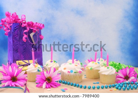 Birthday Cupcakes with Ribbons and Beads on Blue Textured Background