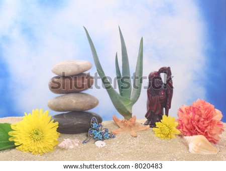 Buddha with Aloe Vera Plant and Flowers on Sand With Blue Background