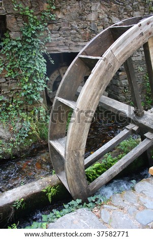 Old watermill with a wooden wheel and stone walls