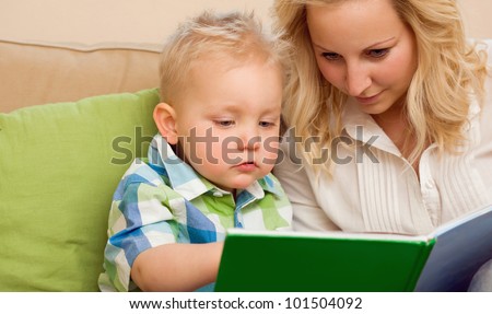 Portrait of a mother and son reading a book together at home.