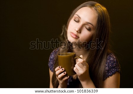Striking beautiful young brunette with mug of steaming hot beverage.
