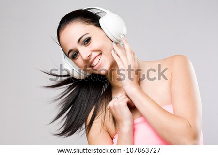 Portrait of a brunette beauty enjoying music in white headphones.