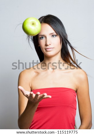 Gorgeous young brunette juggling green apple.