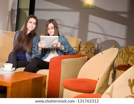 Two girls getting lost in and separated by their mobile devices.