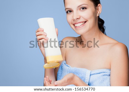 Portrait of a beautiful young brunette woman using skin care product.