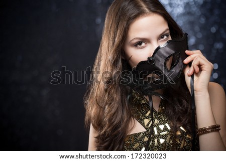 Elegant gorgeous young brunette woman hiding behind festive mask.