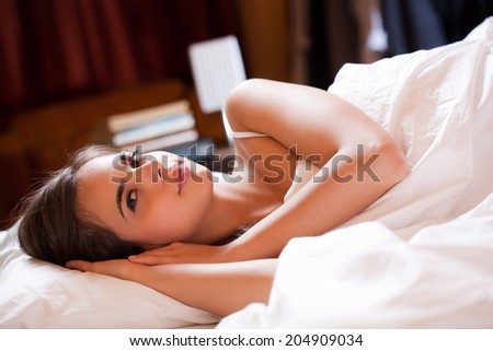 Beautiful young brunette woman laying in bed going to sleep.