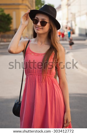 Gorgeous brunette model woman outdoors wearing pink summer dress.