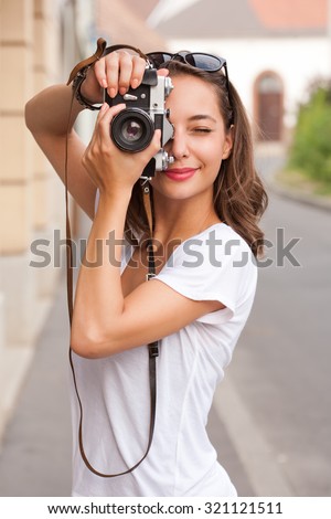 Gorgeous young brunette woman using analog camera.