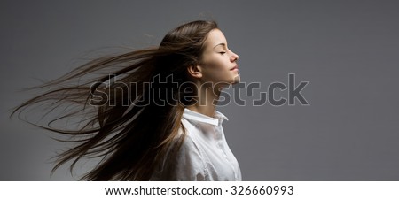Portrait of a young dreamy brunette beauty with windswept hair.