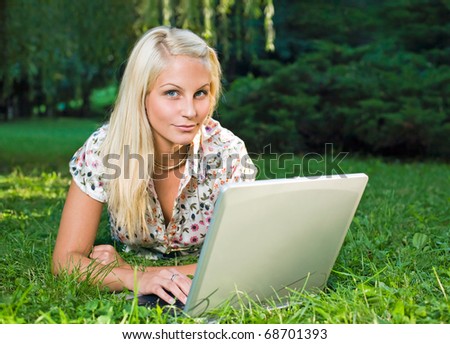 Beautiful young blond using laptop outdoors in nature.