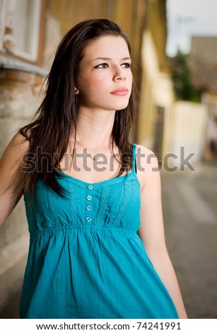 Outdoor portrait of gorgeous young brunette with striking look, serious facial expression.