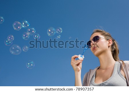 Gorgeous young brunette girl blowing bubbles in to the sky.