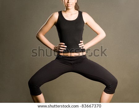 Slender fit young brunette in yoga squat pose.