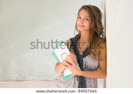 Portrait of a gorgeous young student girl holding exercise books.