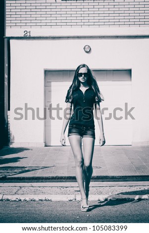 young woman with sunglasses walk down the street, summer day, black and white
