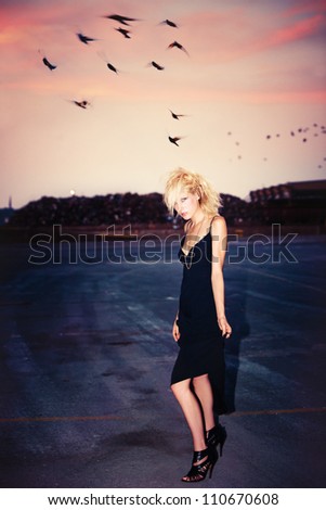 blond fashion model in short black dress and punk hairstyle outdoor shot at dusk