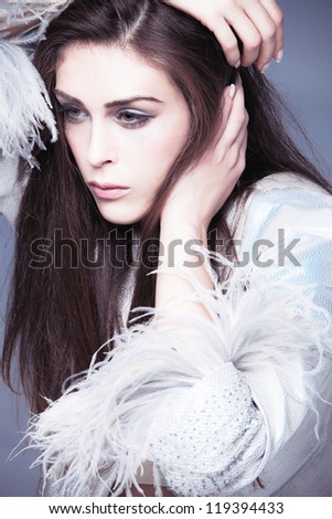 fashion woman portrait   in elegant silver dress with feathers on the sleeves studio shot