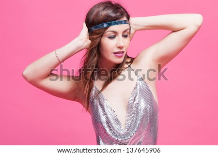 young woman in hippie style dance, studio shot pink background
