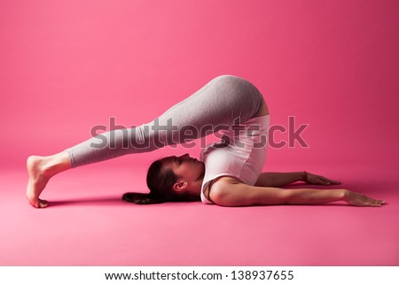 young woman exercise reversed positions studio shot pink background