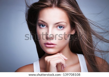 natural looking blue eyes young blond woman with fluttering hair  beauty portrait studio shot