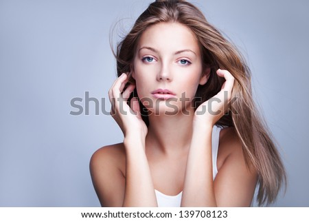natural looking blue eyes young blond woman with fluttering hair  beauty portrait studio shot
