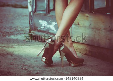 woman  legs in high heel shoes against old door with glass  outdoor shot retro colors