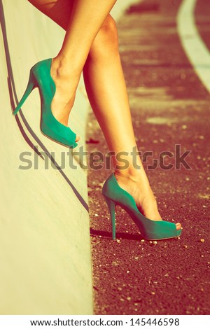 woman tan legs in high heel green shoes outdoor shot  summer day