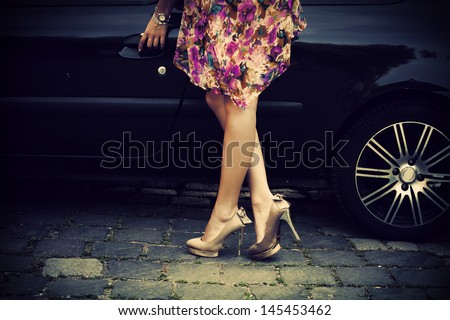 elegant woman in high heel shoes getting into car