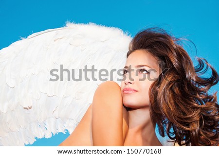 beautiful angel woman with white wings against blue sky small amount of grain added