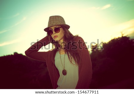 young hipster woman with hat and sunglasses outdoor shot at sunset retro colors