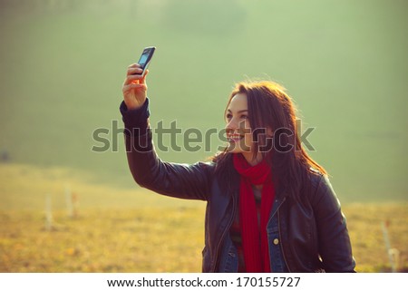 young smiling girl in casual clothes take photo with mobile phone outdoor shot