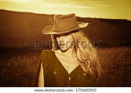 young woman in cowboy style clothes outdoor at sunset