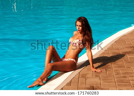 woman in bikini by the  pool hot summer day
