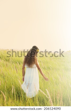 young woman in boho style clothes walk  through the field, back shot, sunny summer day, retro colors