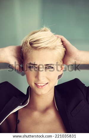 smiling young blue eyes woman with trendy short blonde hair  outdoor portrait recline on glass window hands in hair