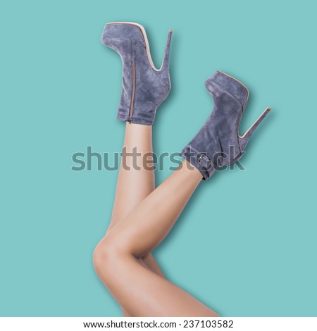 woman legs in velour high heel platform ankle boots lean on pastel blue wall upside down