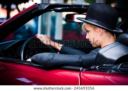 young urban fashion woman driving red cabrio through the city
