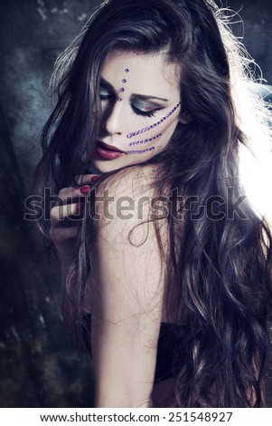 beautiful young fairy like woman with long hair and fantasy make up and purple zircons on face, studio shot