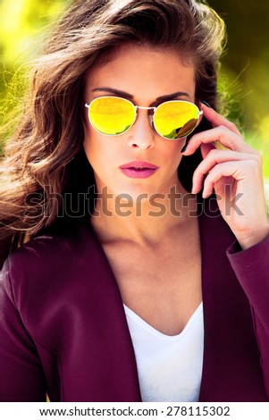 young urban fashion woman wearing yellow sunglasses and purple jacket, outdoor shot in the city
