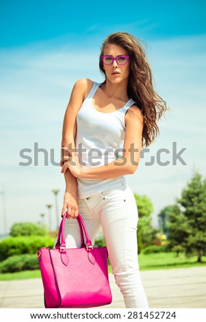 young woman in casual outfit  white jeans and top tank and pink bag outdoor in the city summer day