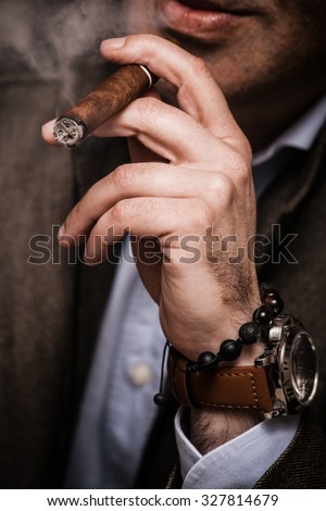 elegant man wearing suit and white shirt smoking  cigar indoor shot, closeup, selective focus