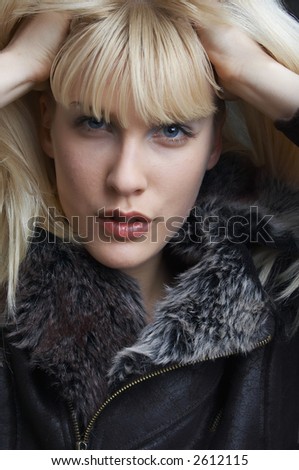 blond girl in jacket with hands in blond hair