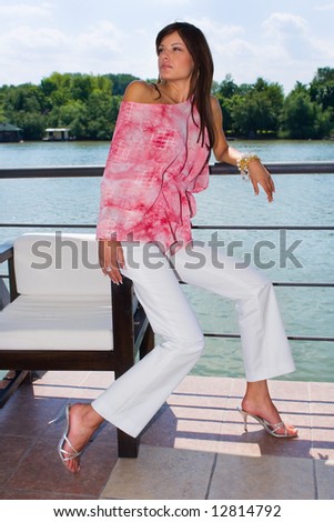 elegant young woman in summer clothes, on a terrace by the river