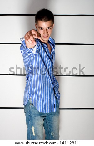young suspicious man in police station in line up, pointing with finger