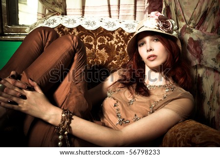 young elegant woman with hat sit in armchair, indoor shot