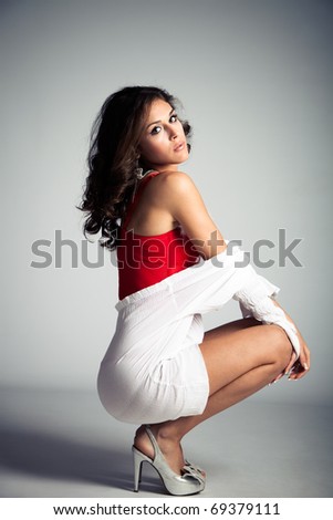 young brunette woman in white shirt and red corset, full body shot, studio shot